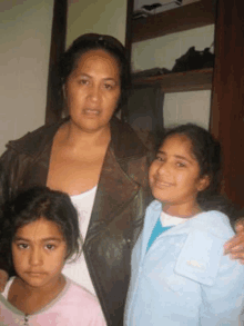 a woman in a leather jacket is posing for a picture with two little girls