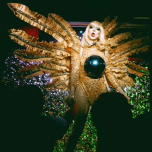 a drag queen in a gold costume with a disco ball on her chest