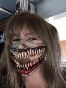 a woman is wearing a mask that looks like a monster with huge teeth