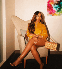 a woman is sitting in a chair with her legs crossed and holding a gold purse