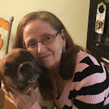 a woman is holding a brown dog in her arms .