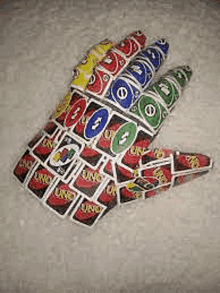 a hand made out of uno cards is laying on a table .