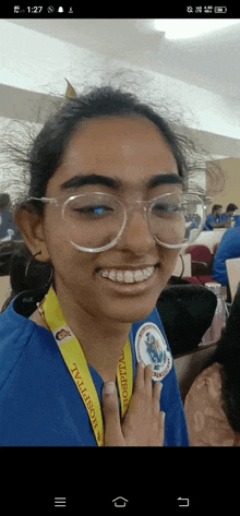 a woman wearing glasses and a hospital lanyard smiles