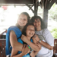 a group of three women are hugging each other and smiling for a picture .