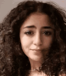 a close up of a woman with curly hair and a necklace .