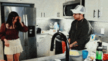 a man and a woman are standing in a kitchen and the man is wearing a hat that says ' i love you '