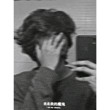 a person covering their face with their hand in front of a mirror with chinese writing on it