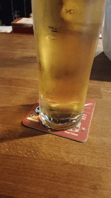 a glass of beer sits on a coaster that says " tokyo football "