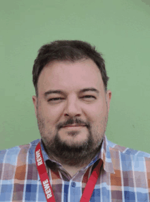 a man wearing a plaid shirt and a red reinwe lanyard