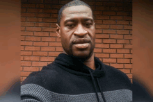 a man standing in front of a brick wall