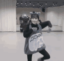 a girl in a totoro costume is dancing in a room .