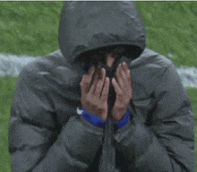 a person wearing a hooded jacket is covering their face