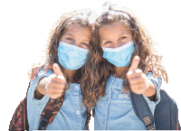 two young girls wearing face masks are giving a thumbs up