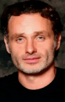 a close up of a man 's face with a beard and a black shirt .