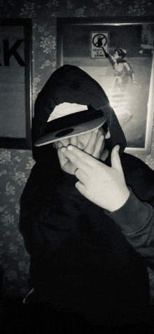 a black and white photo of a person covering their face with their hand