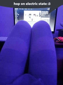 a person wearing purple socks sits in front of a computer screen that says electric state on it