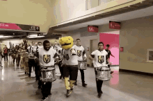 a group of people playing drums in a hallway with a sign that says men 's and women 's restrooms