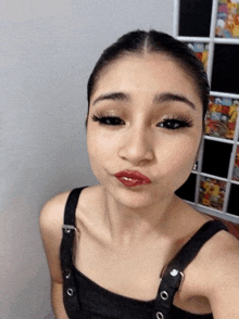 a woman wearing a black tank top and red lipstick takes a selfie