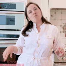 a woman in a white shirt is standing in a kitchen with the words good housekeeping on the bottom right