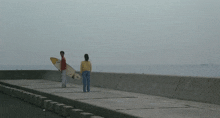 a man and a woman standing on a pier holding surfboards one of which has the letters s on it