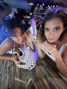 two women are sitting at a table in a crowded bar