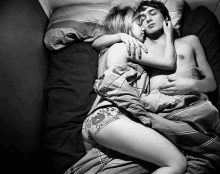 a black and white photo of a man and a woman hugging in bed