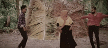 a man and two women are dancing in front of a palm tree