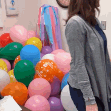 a woman is standing in front of a bunch of balloons one of which says ' i love you ' on it