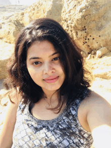 a woman taking a selfie in front of a rock wall