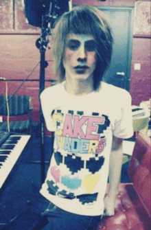 a boy wearing a fake invaders shirt stands in front of a keyboard