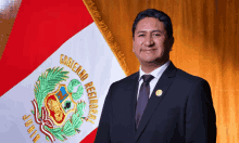 a man in a suit and tie stands in front of a flag that says " gobierno regional "