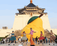 a group of people are dancing in front of a giant pear that says jo malone