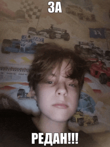 a boy laying on a bed with a picture of a race car in the background and a caption that says " 3a redah "