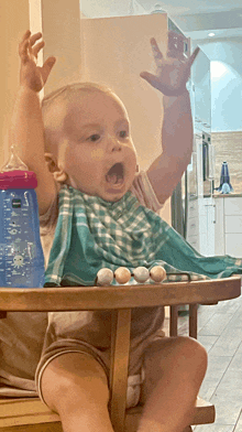 a baby sitting in a high chair with his mouth open