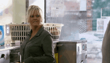 a woman stands in front of a laundromat with a sign on the window that says ' free of charge ' on it