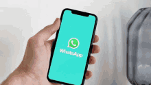 a person is holding a cell phone with the whatsapp app on the screen