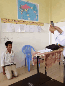 a person taking a picture of a boy in front of a map