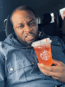 a man in a car holding a starbucks drink