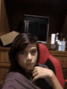 a young boy sits in a red chair in front of a computer