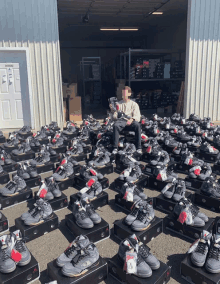 a man sits on a pile of boxes of shoes