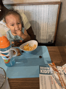 a toddler sitting at a table with a broken kids menu