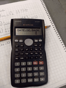 a casio calculator is on top of a notebook