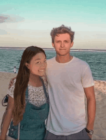 a man and a woman pose for a picture on a beach