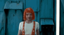 a man wearing a red wig and a white shirt is standing in front of a blue wall .