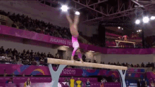 a female gymnast is doing a handstand on a balance beam in front of a crowd at a 2019 competition