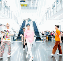 a group of young men are dancing in front of an escalator with a sign above them that says ' disneyland '