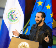 a man stands at a podium with a flag behind him that says republica de el salvador