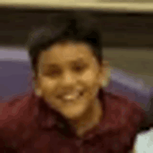 a close up of a young boy wearing a red shirt smiling .