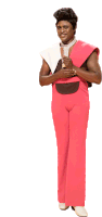 a man wearing pink pants and a white shirt is standing with his hands folded