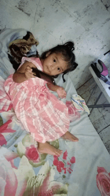 a little girl in a pink dress is laying on a bed with roses on it